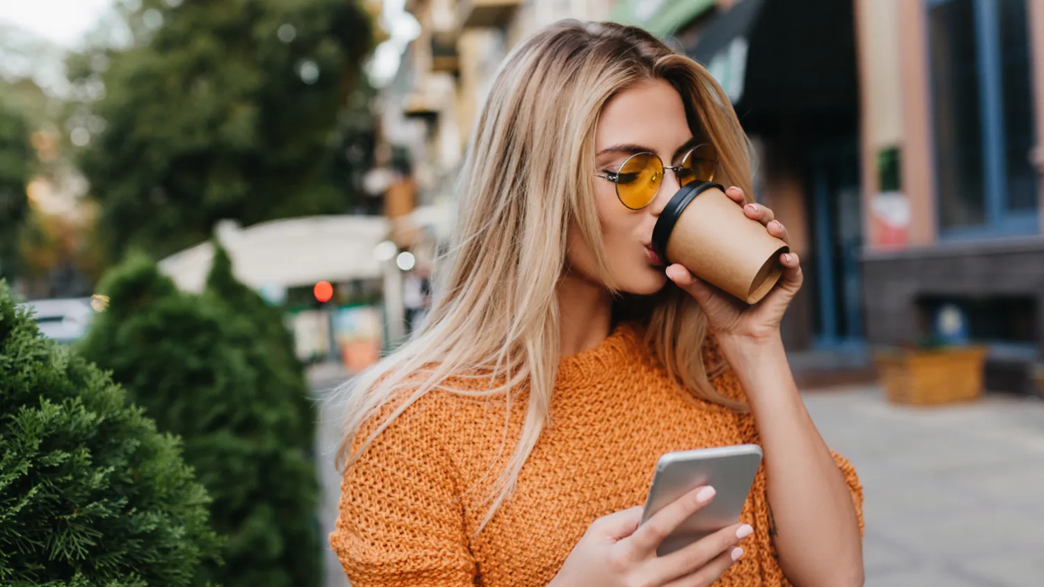 Pige med kaffe kigger på sin telefon